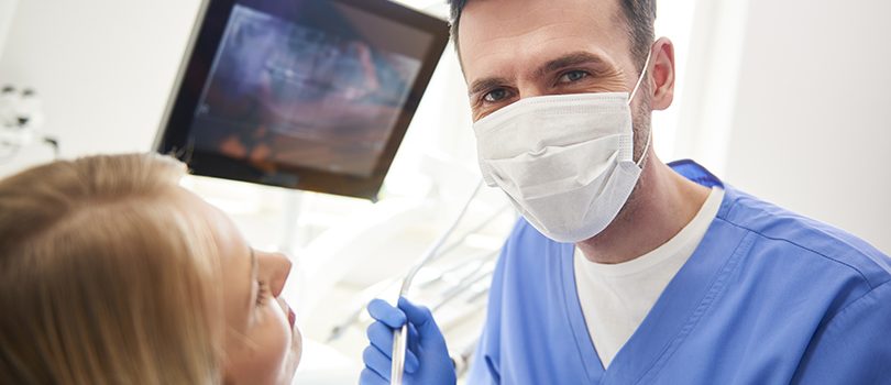 Portrait of confident dentist using dental drill and dental mirror