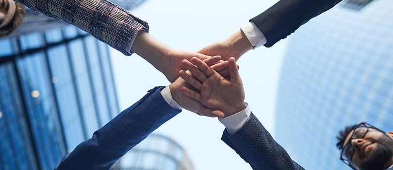 Low angle view of business team holding hands they uniting and supporting each other in the city